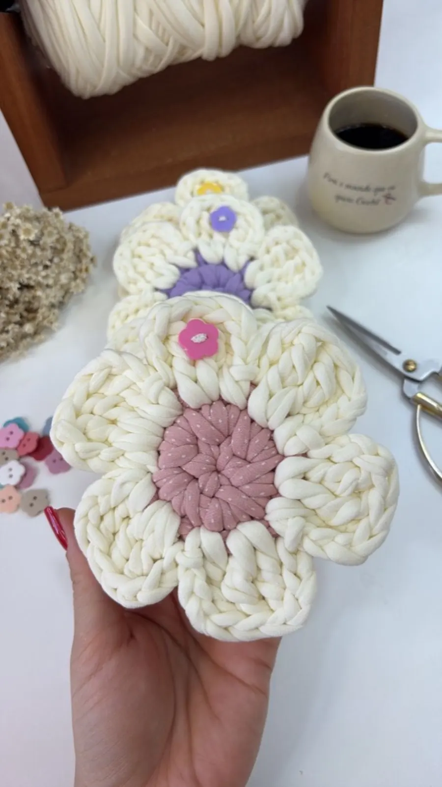 Porta-copos em formato de flor em fio de malha cru com miolos rosa, lilás e amarelo e botões decorativos